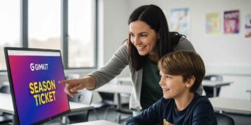 A photo of a teacher and student engaged with a computer screen showing the Gimkit Season Ticket interface in a bright, modern classroom.