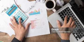 Business man using computer and calculator to developing a business project and analyzing market data information. Top view