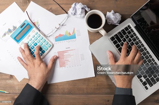 Business man using computer and calculator to developing a business project and analyzing market data information. Top view