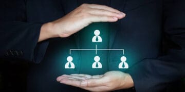 Business man holding team member icon on hands; Teamwork and organization concept